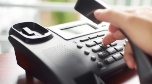 Auf einen Telefon wählt sich ein Mann in einer internationale Telefonkonferenz